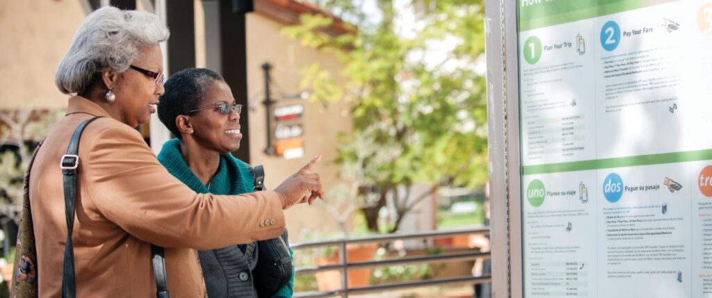 Two seniors viewing Metro System information in display case on the platform.