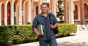 College student holding books on a college campus.