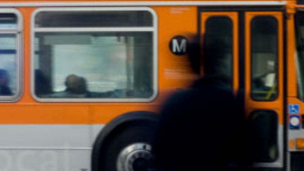 Passenger with Metro Local vehicle passing in background.
