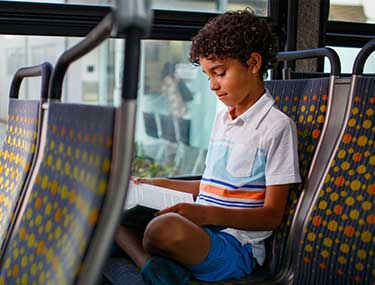 Young rider reading a book on a Metro rail vehicle.