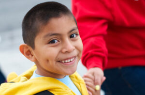 Young boy holding mom's hand and smiling.