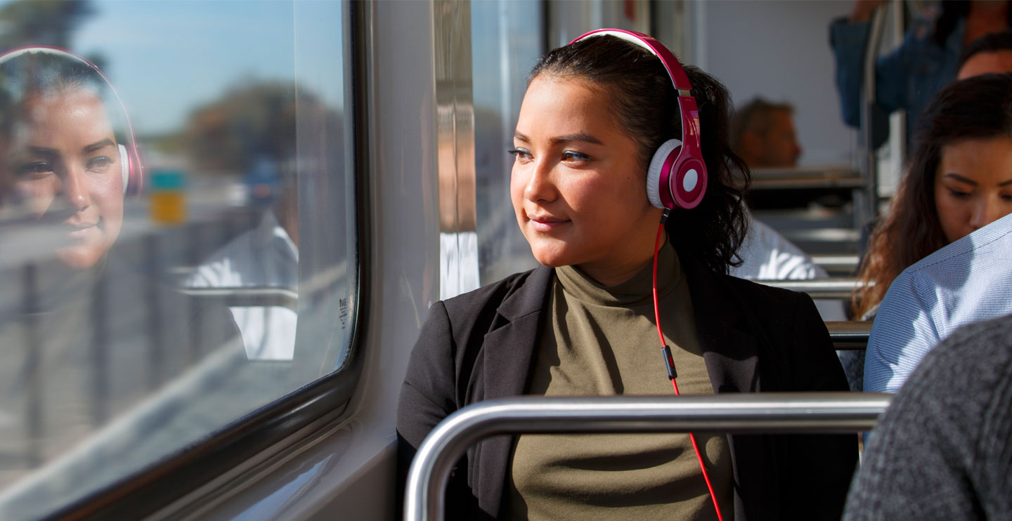 A young woman riding a Metro Rail vehicle staring out of the window.