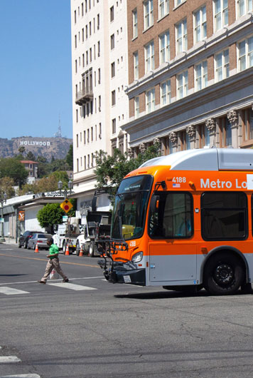 Metro Local bus passing through an intersection near the Hollywood sign.